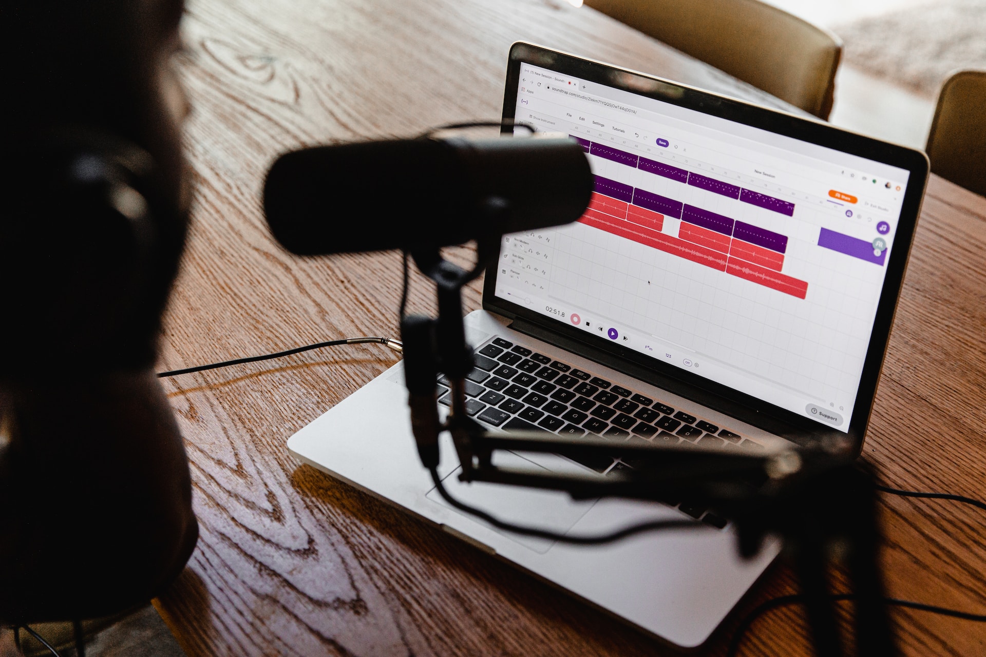 description: image of a podcasting microphone on a desk, in front of a laptop.  Photo by Soundtrap on Unsplash.